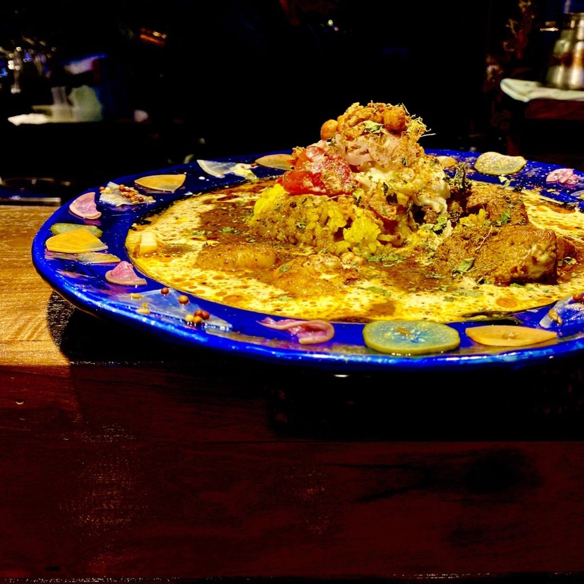灯りを落とした店内の木のカウンターに置かれた、藍色の大皿に盛られたスパイスカレー